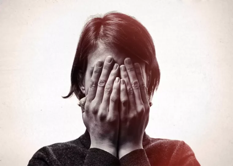femme aux cheveux courts qui cache son visage avec les deux mains