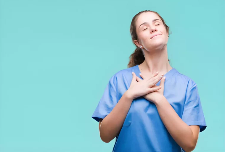 femme avec une blouse bleue tient ses mains sur sa poitrine et sourit avec les yeux fermes sur fond vert