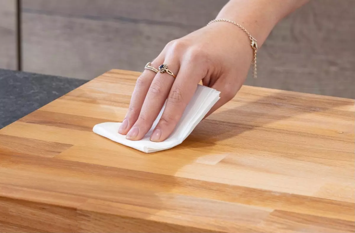 main qui frotte avec du papier blanc une planche en bois