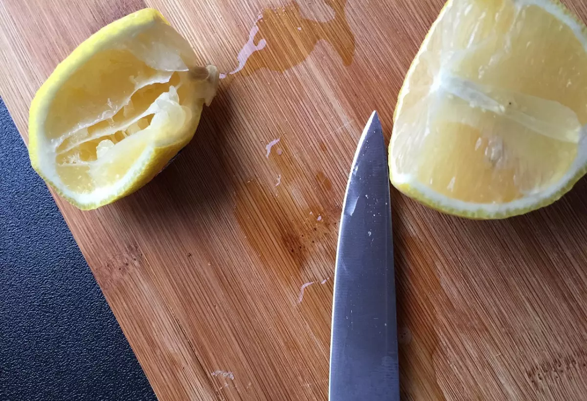 morceaux de citron decoupe avec le jus sur une planche en bois et un bout de couteau