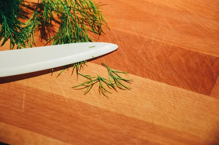 vue de dessus de planche a decouper en bois avec un bout de couteau et des herbes fraiches