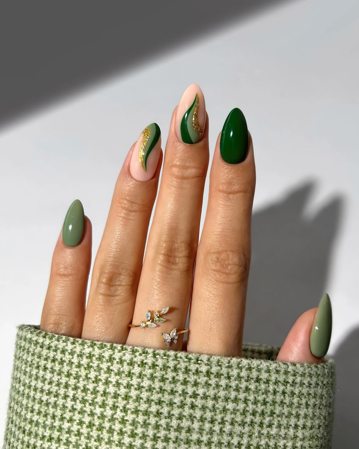 fedvernis vert fonce manucure ongles en amande lignes courbes paillettes dorees