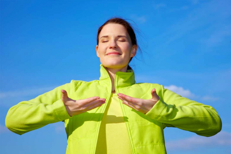 position pour digerer rapidement femme respiration ciel bleu veste verte fluo