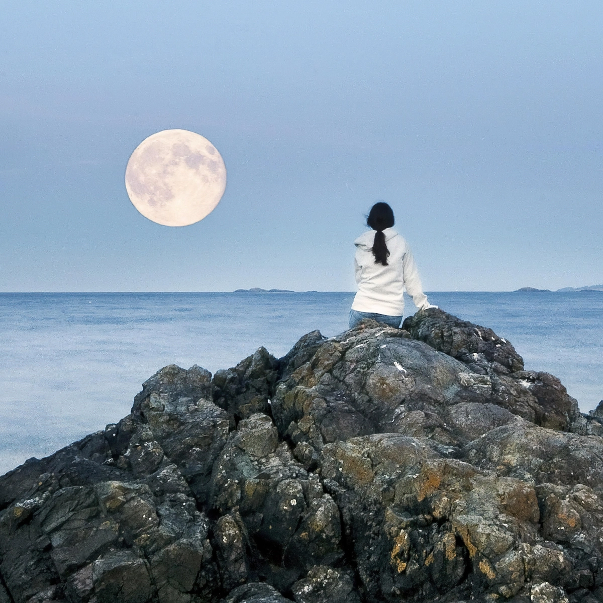 fille assise sur les rochers vue mer eau ciel bleu pleine lune