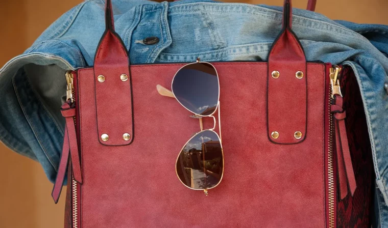 lunettes de soleil aviateur sur sac a main rouge et veste en denim