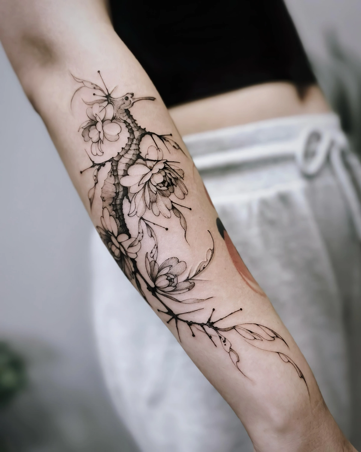 dessin dragon de mer sur avant bras fleurs tiges art corporel