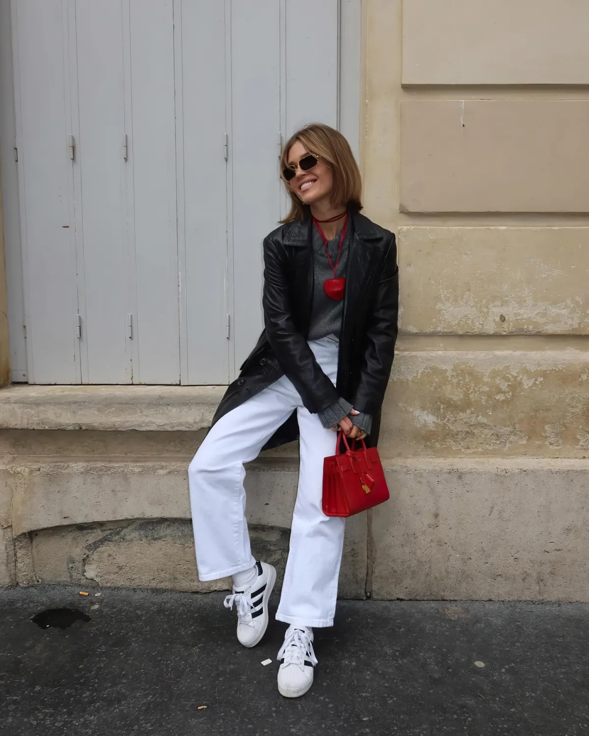 pantalon blanc top gri veste en cuir long noir sac a main rouge