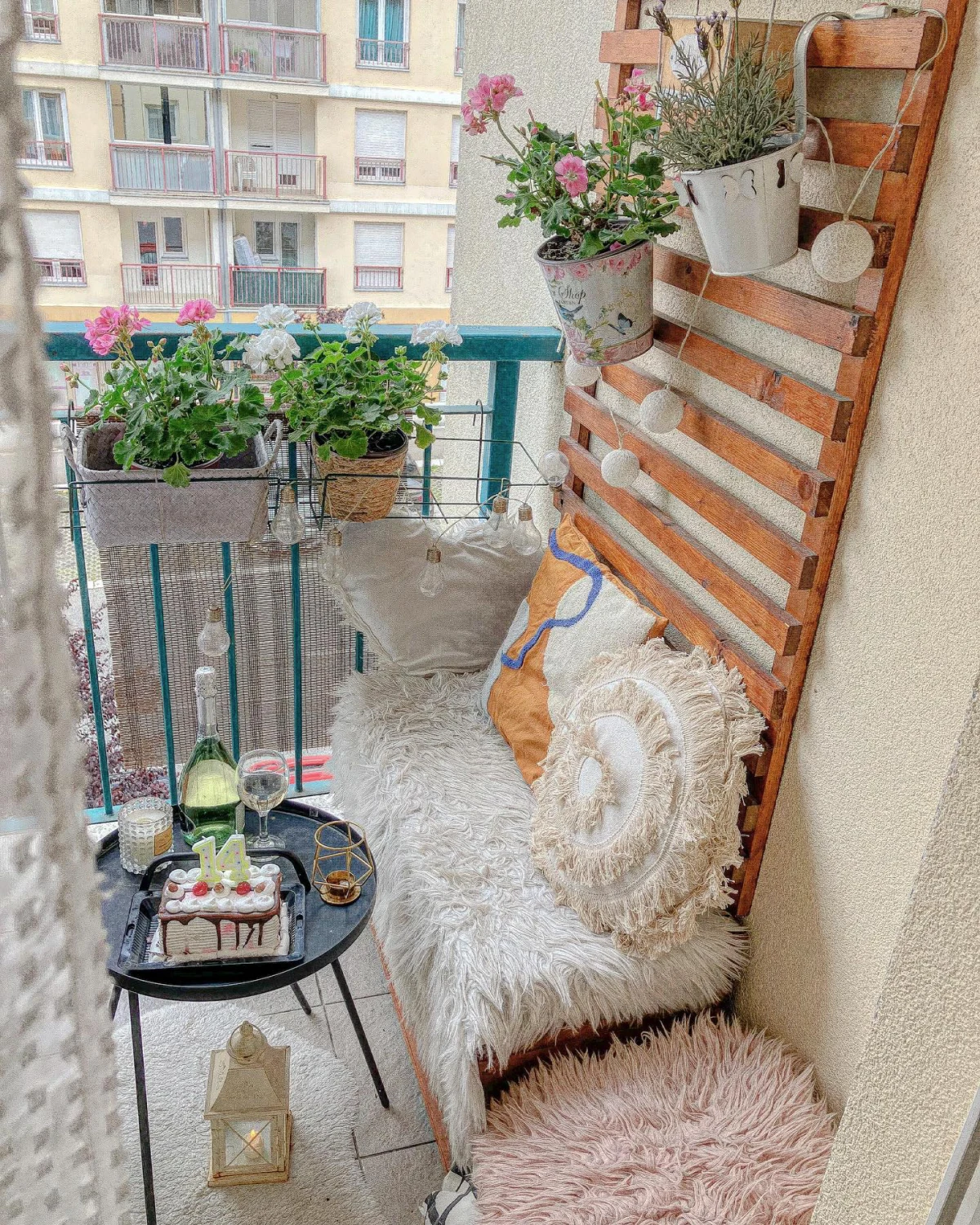 petit balcon trellis banc coussins blanches plantes vertes fleurs roses