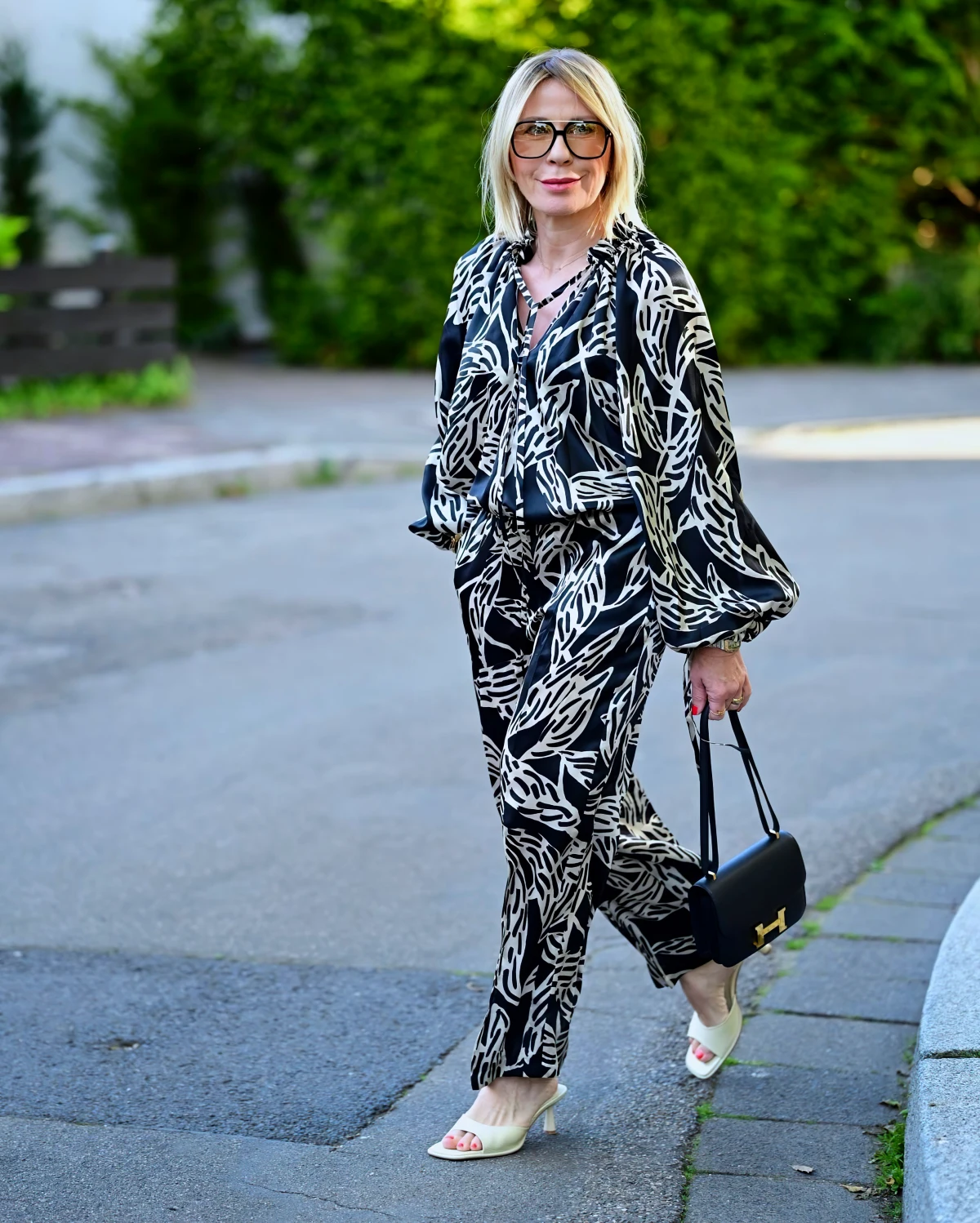 tenue imprime sandales ouvertes sac noir femme 50 ans dans la rue lunettes retro