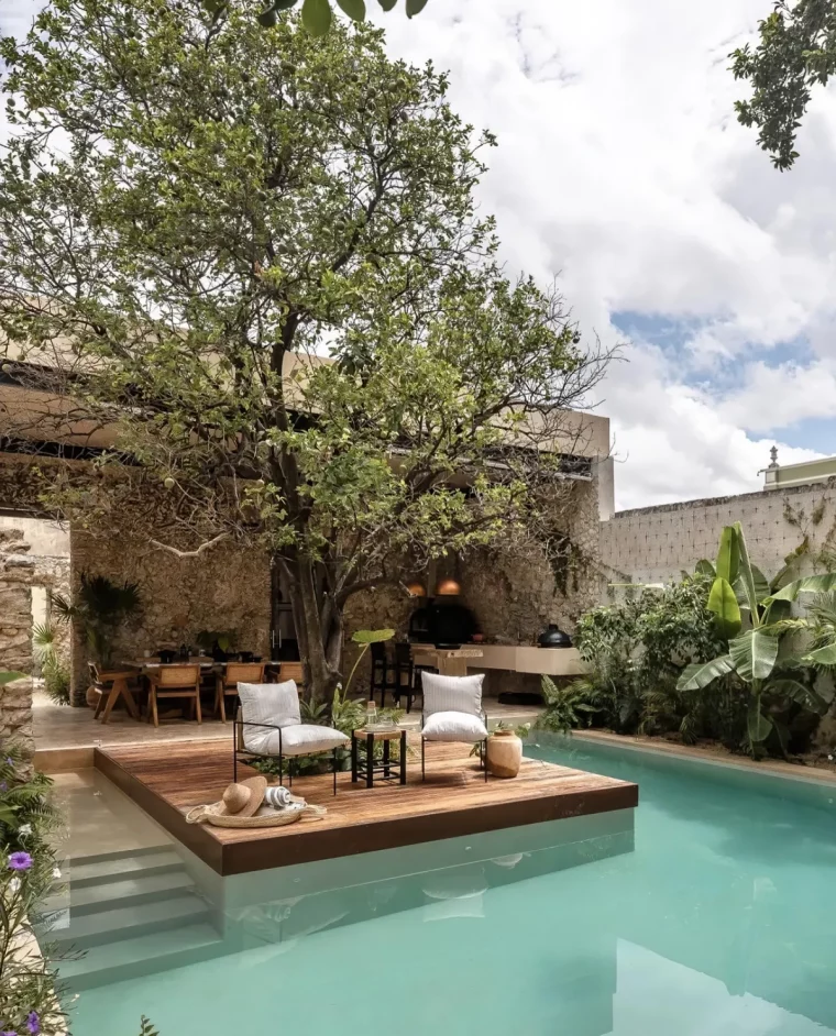 piscine en u avec ilot en bois chaises longues grand arbre