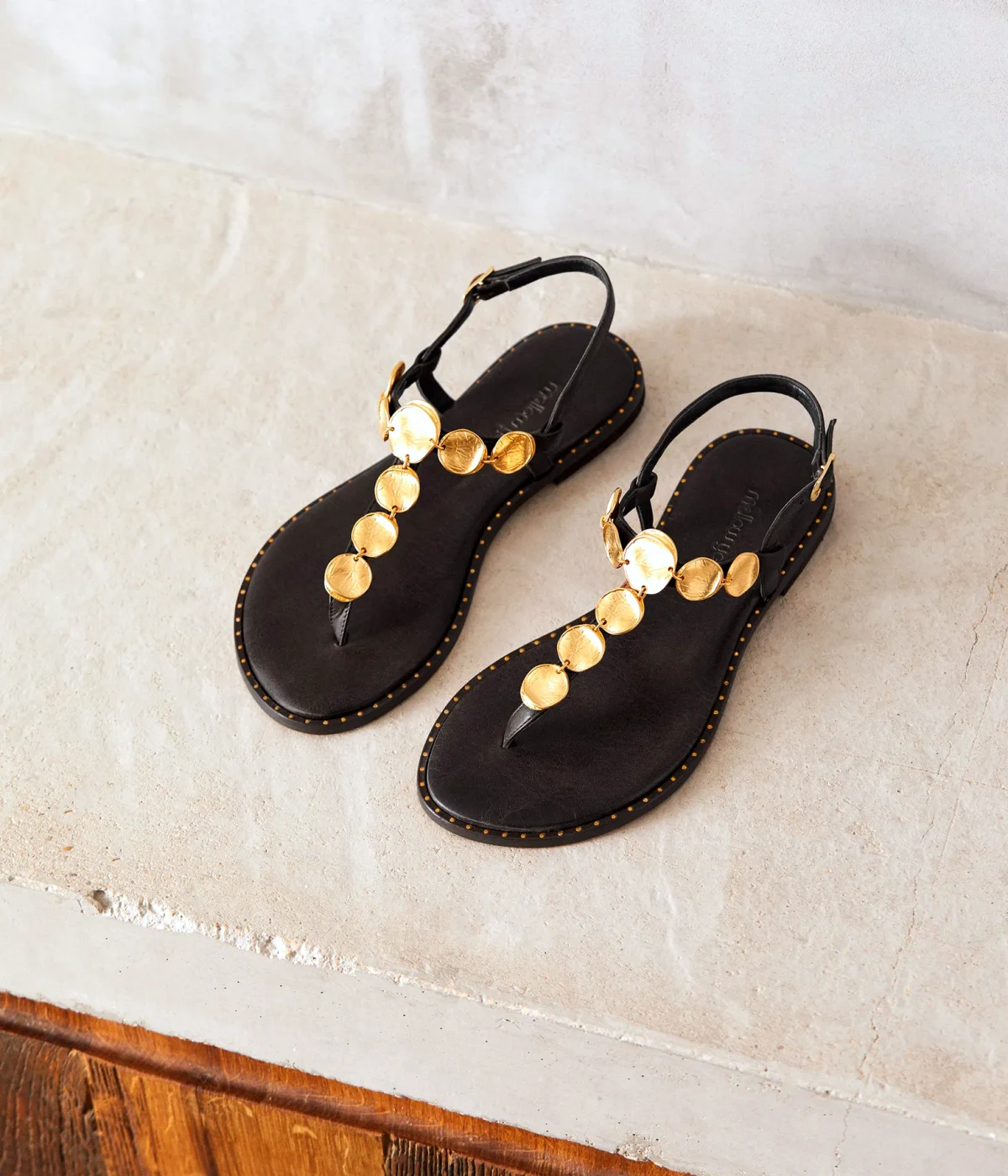 sandales plates noires avec des ornements dorees