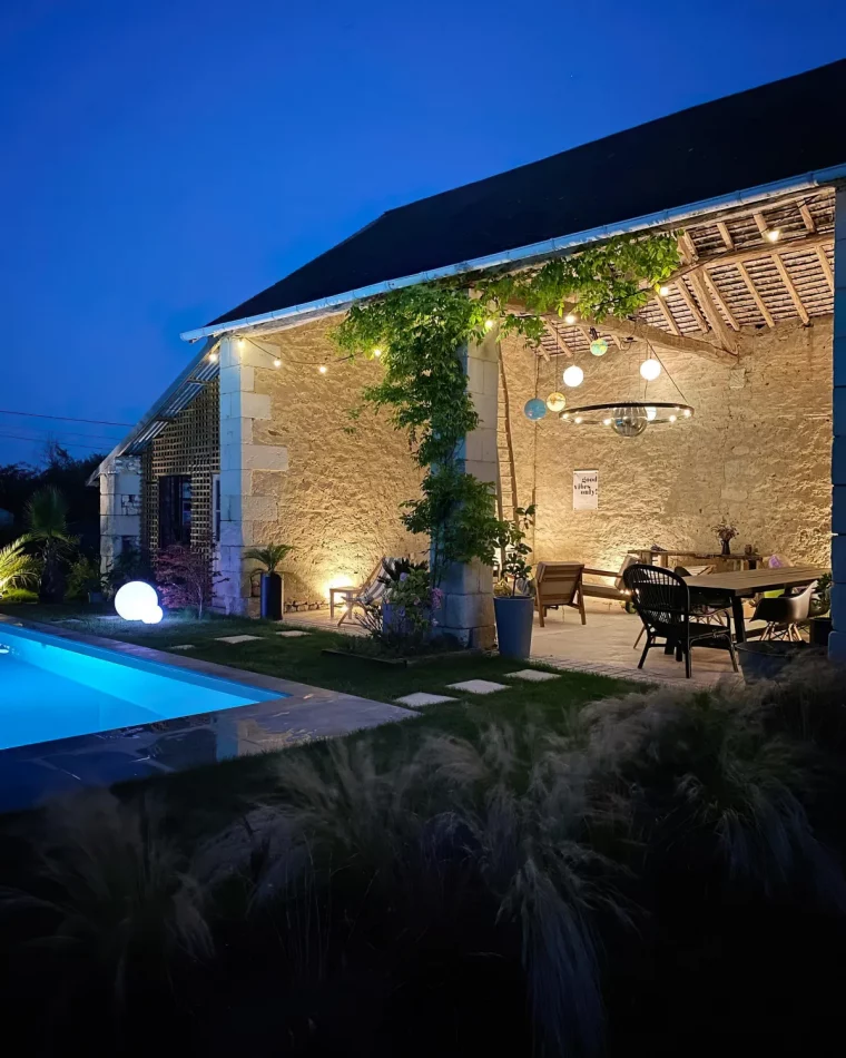 vue sur la piscine et le coin repas au crepuscule lampes