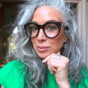 coiffure pour cheveux epais gris femme avec lunettes noires top vert