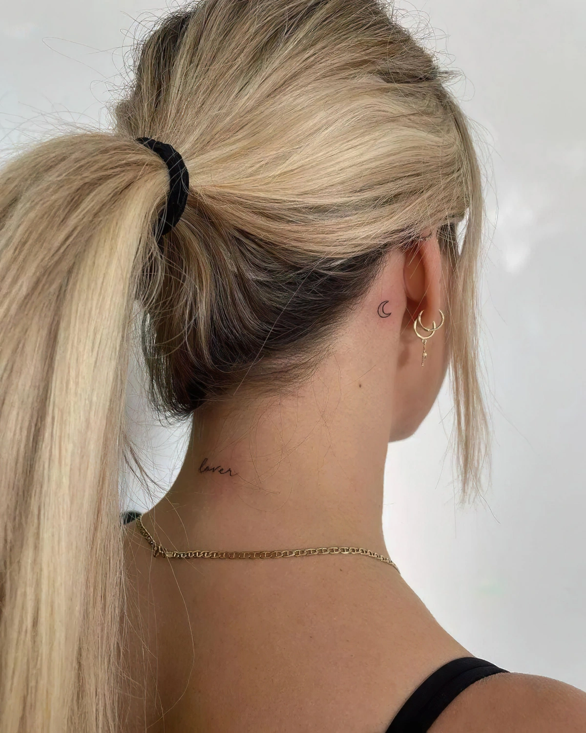 cheveux blonds en queue piercing oreille tatouage lune