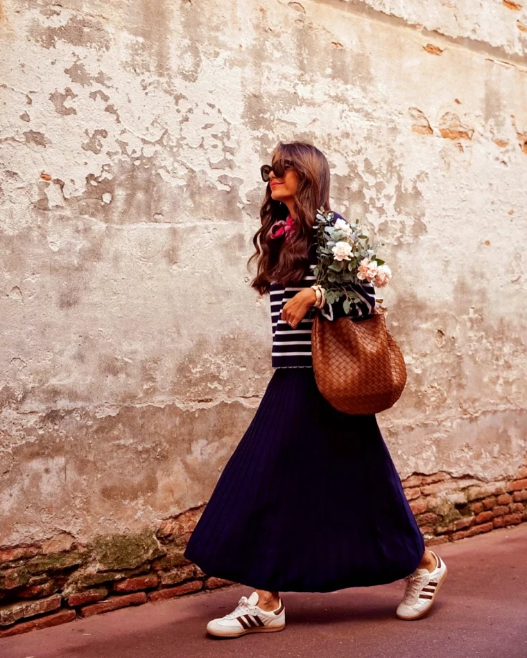 tenue avec une jupe plisse longue pull mariniere femme dans la rue avec un bouquet de fleurs