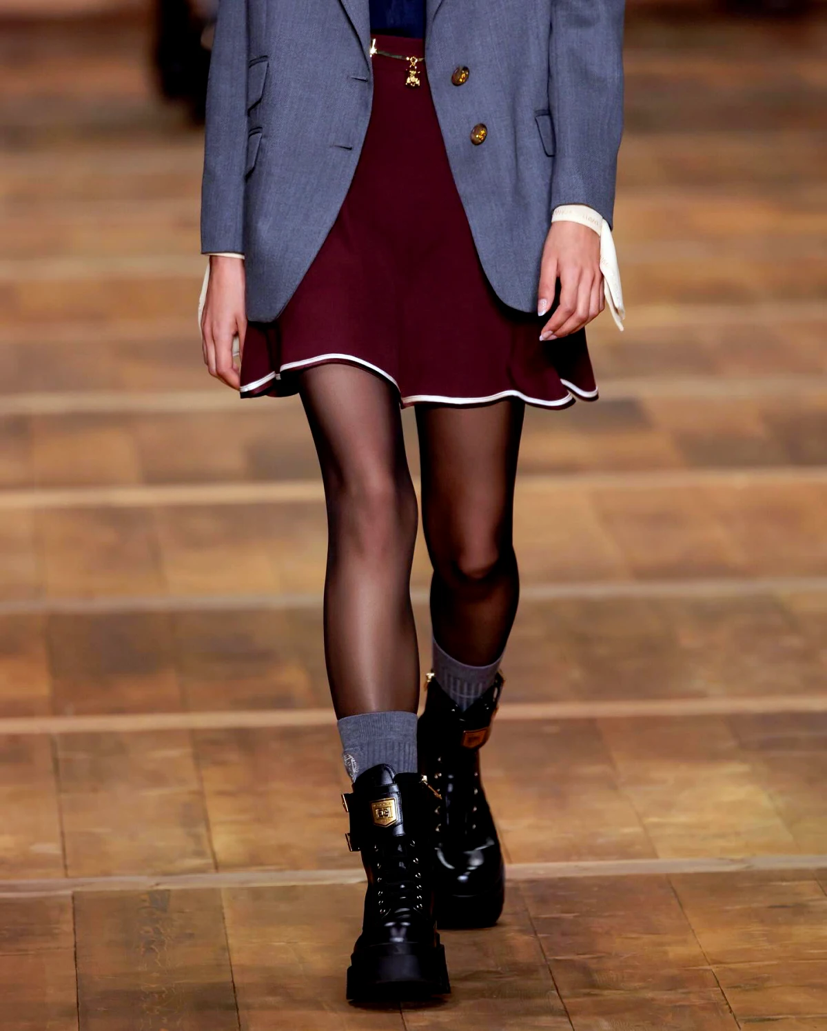 bottines tendances mode hiver 2024 look avec une Jupe courte bordeaux et un tailleur gris