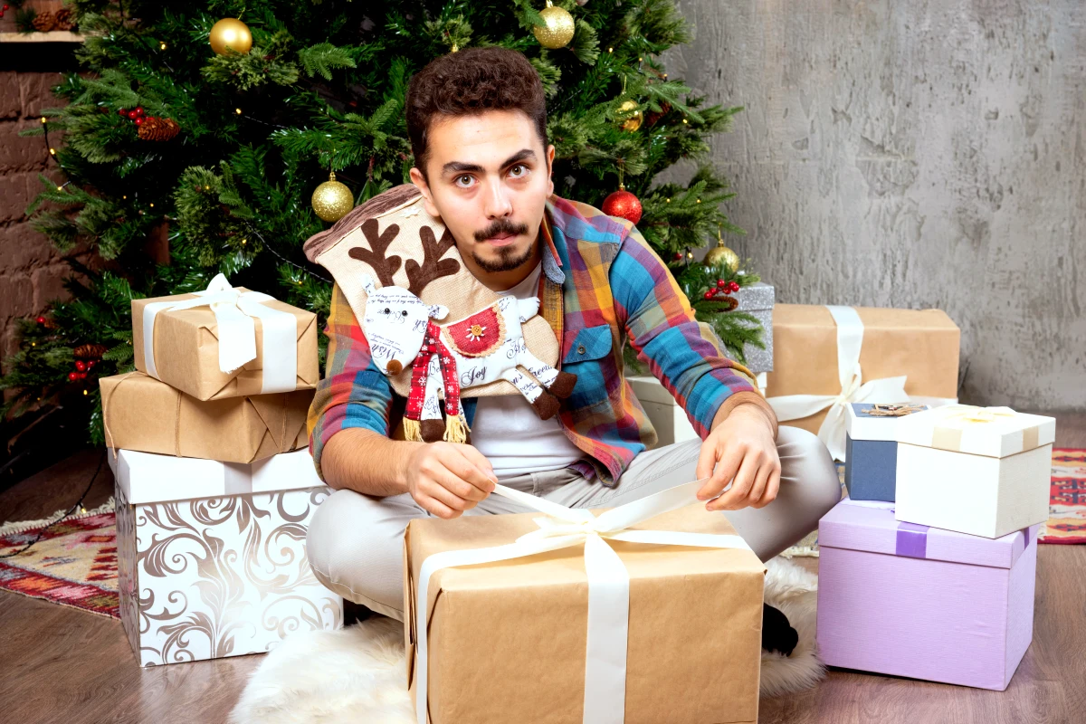 idee cadeau homme noel pas cher un homme barbue devant le sapin avec plein de cadeaux 