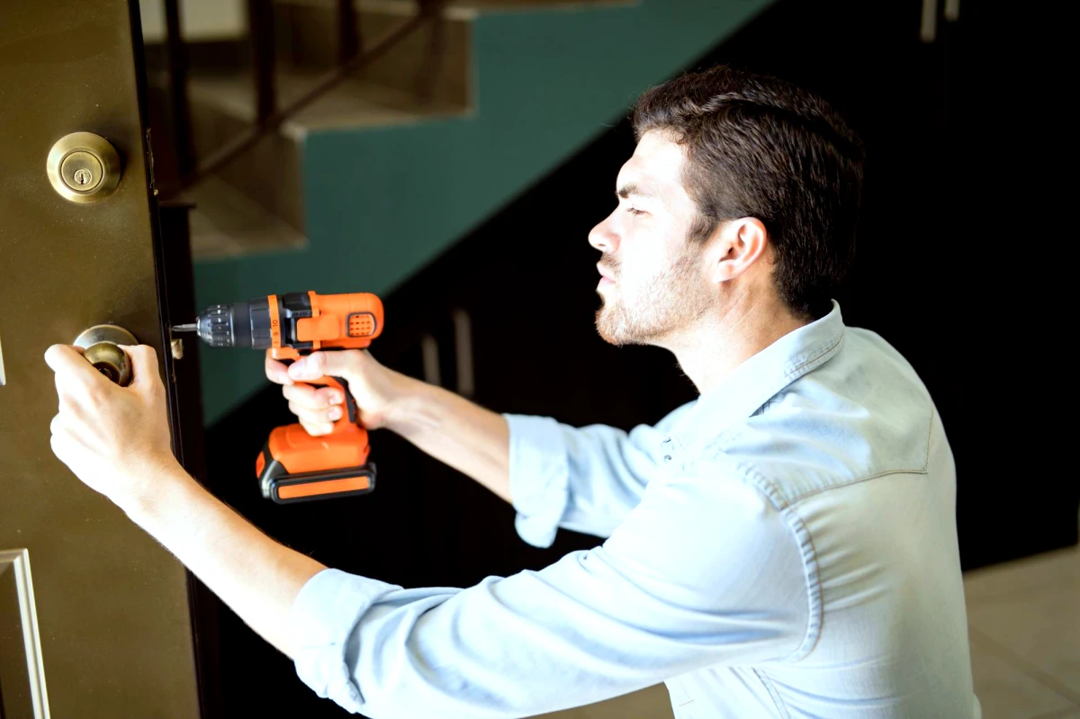 un homme qui repare une serrure avec un outil orange