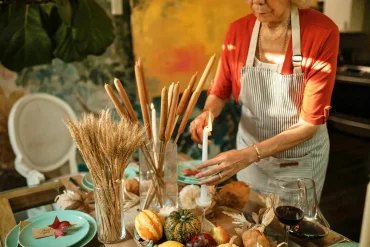 une femme qui alume des bougies festives a la table