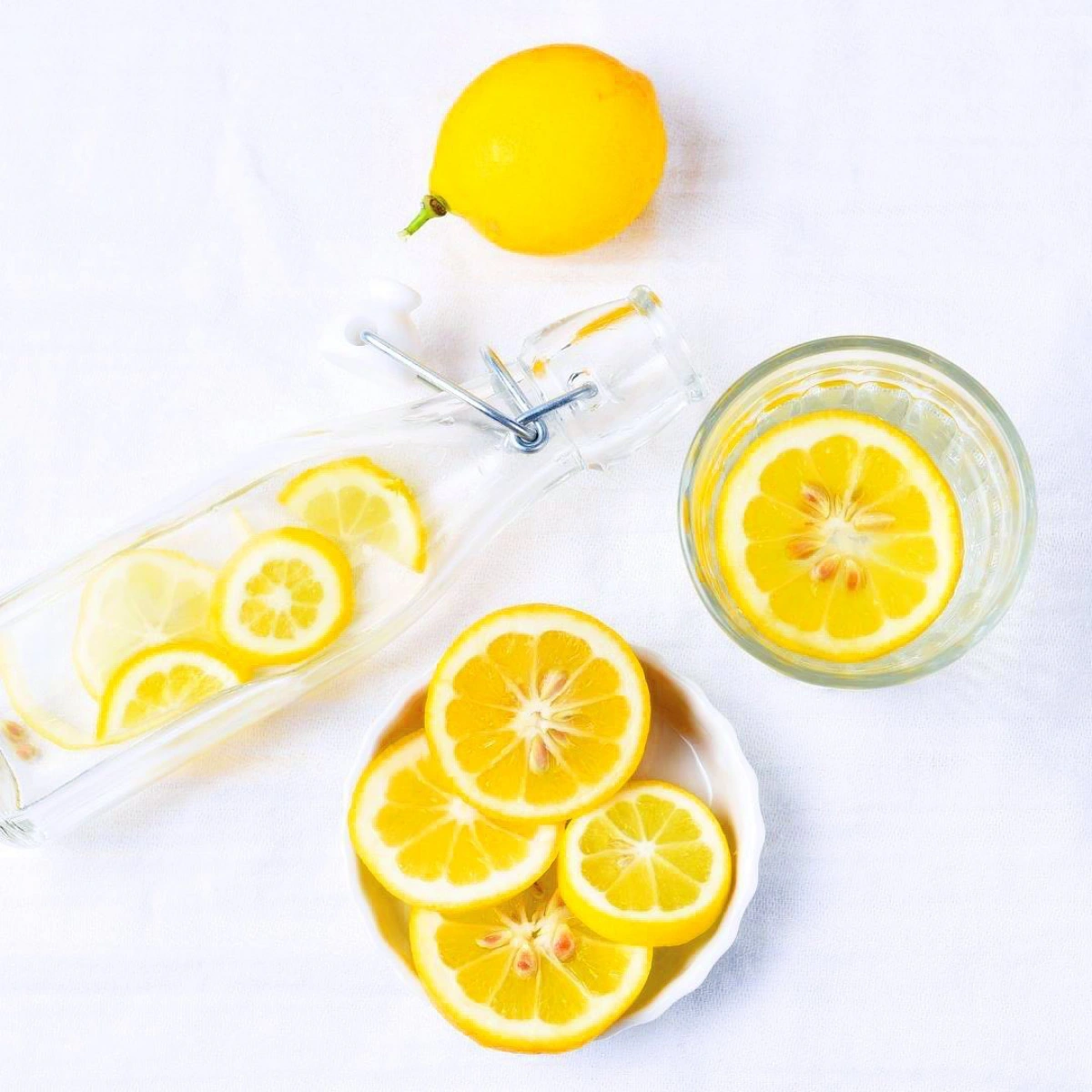 tranches agrumes jus de citron bienfaits surface blanche bouteuille verre