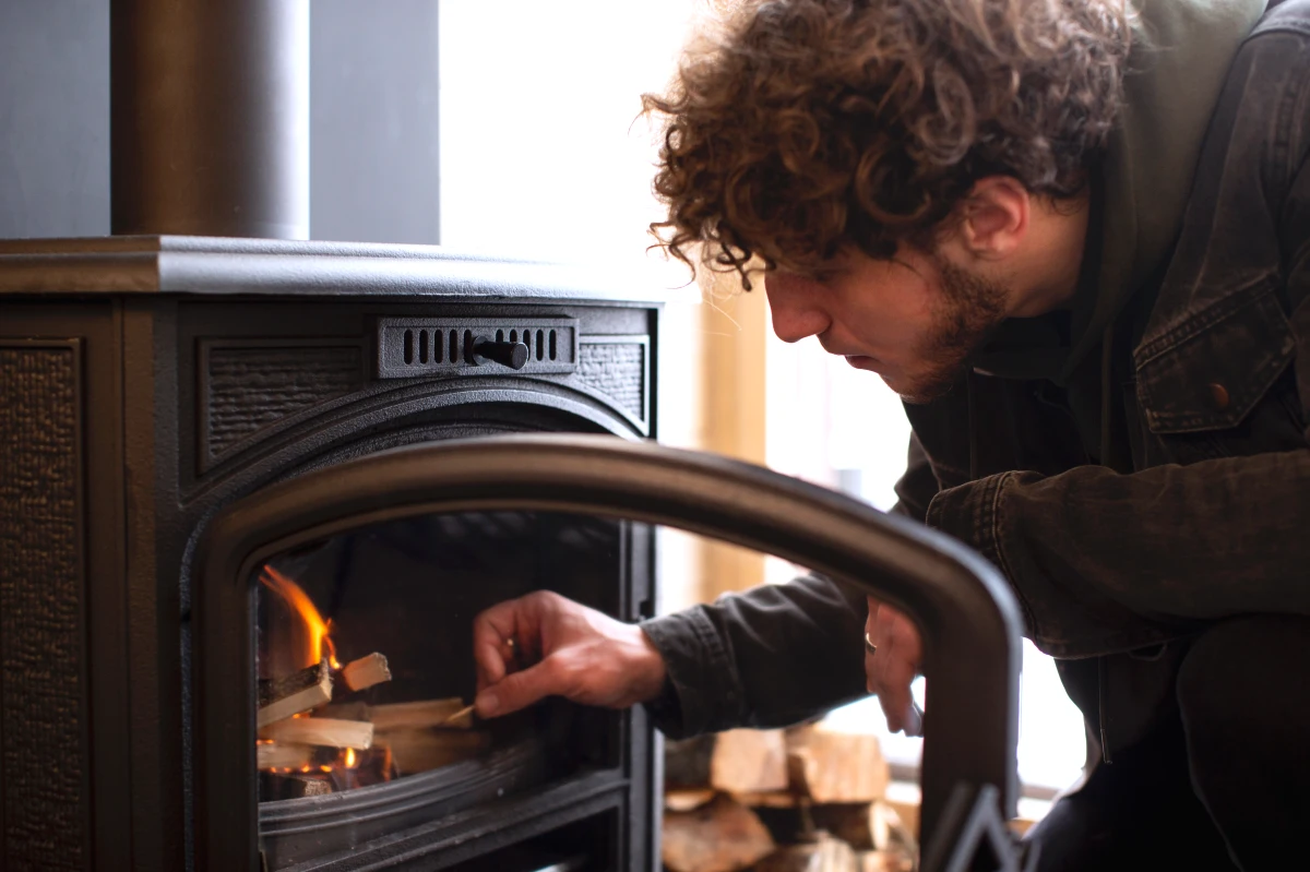 un homme qui allume un poele a bois