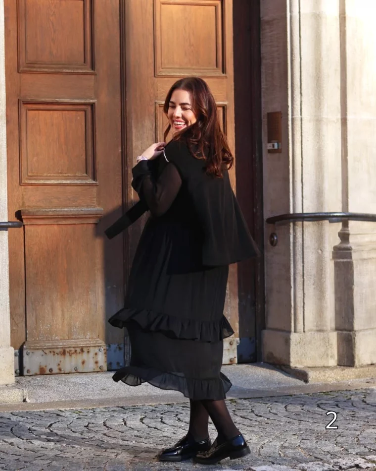 mode femme grande taille brune avec robe noire longue devant une porte